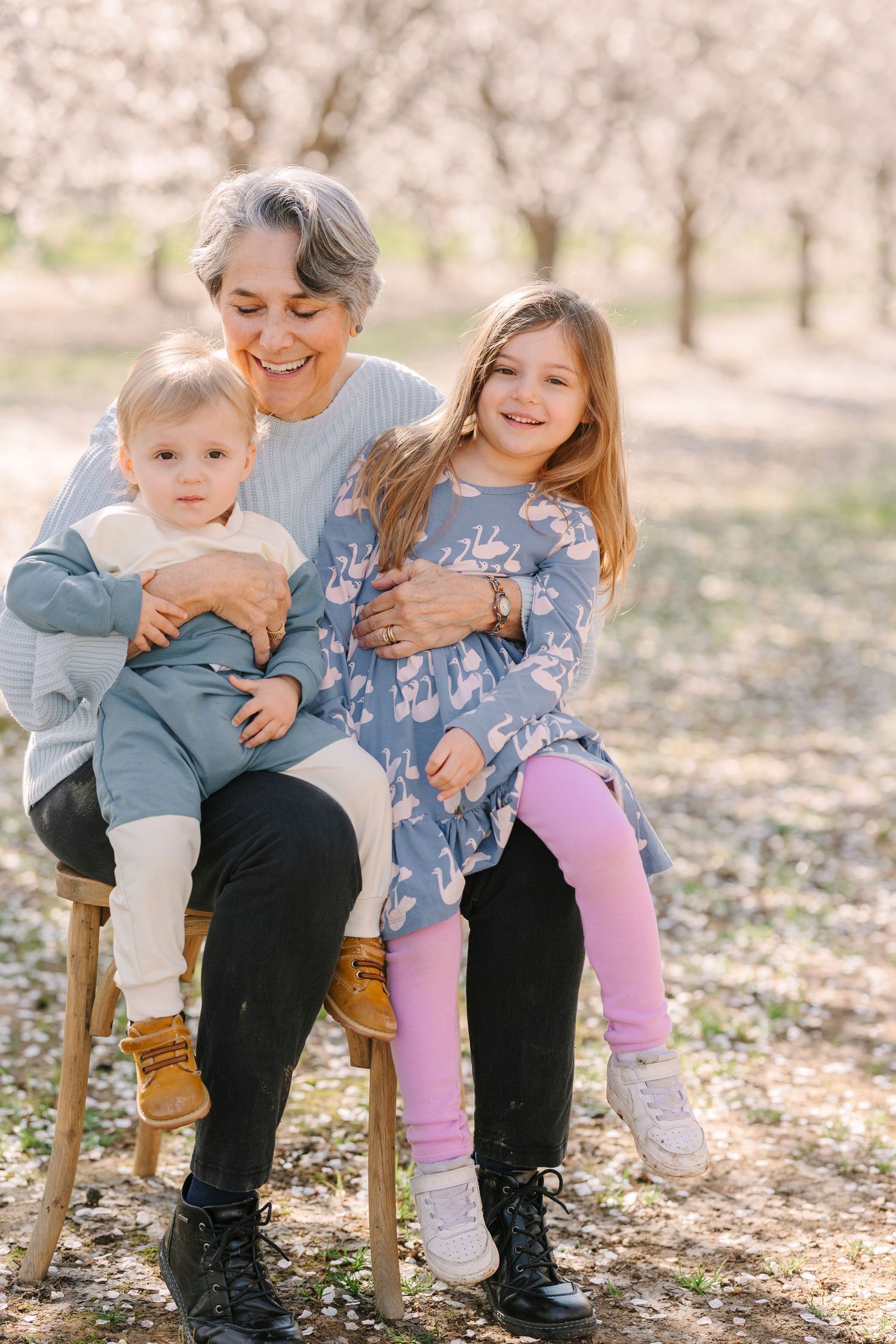 Playful family moments captured on wooden bench under blooming spring trees.
