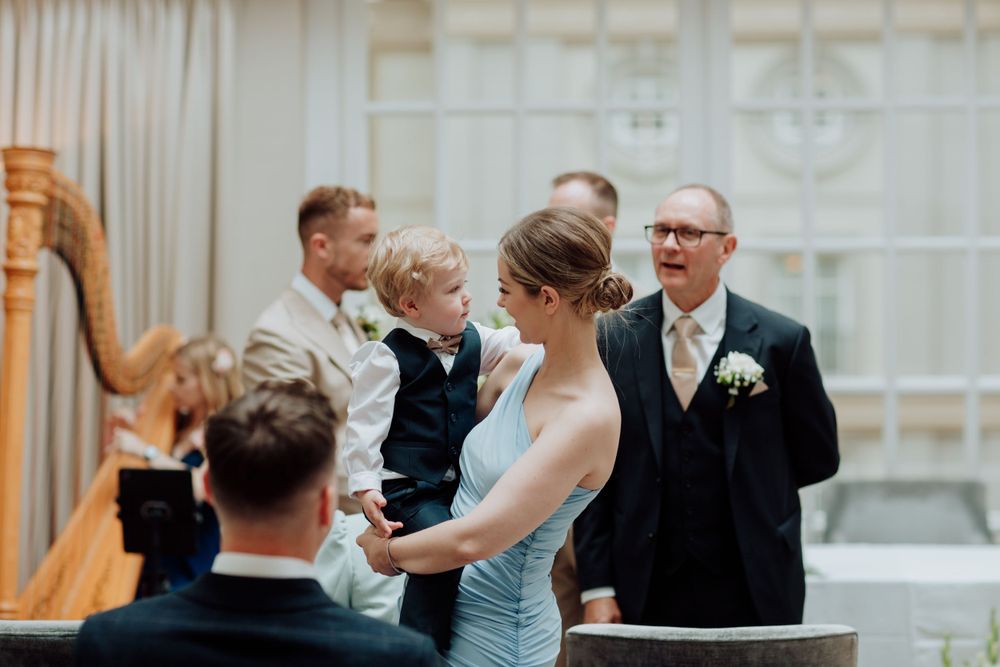Guests and musicians gather at an elegant wedding ceremony with a golden harp in the foreground.