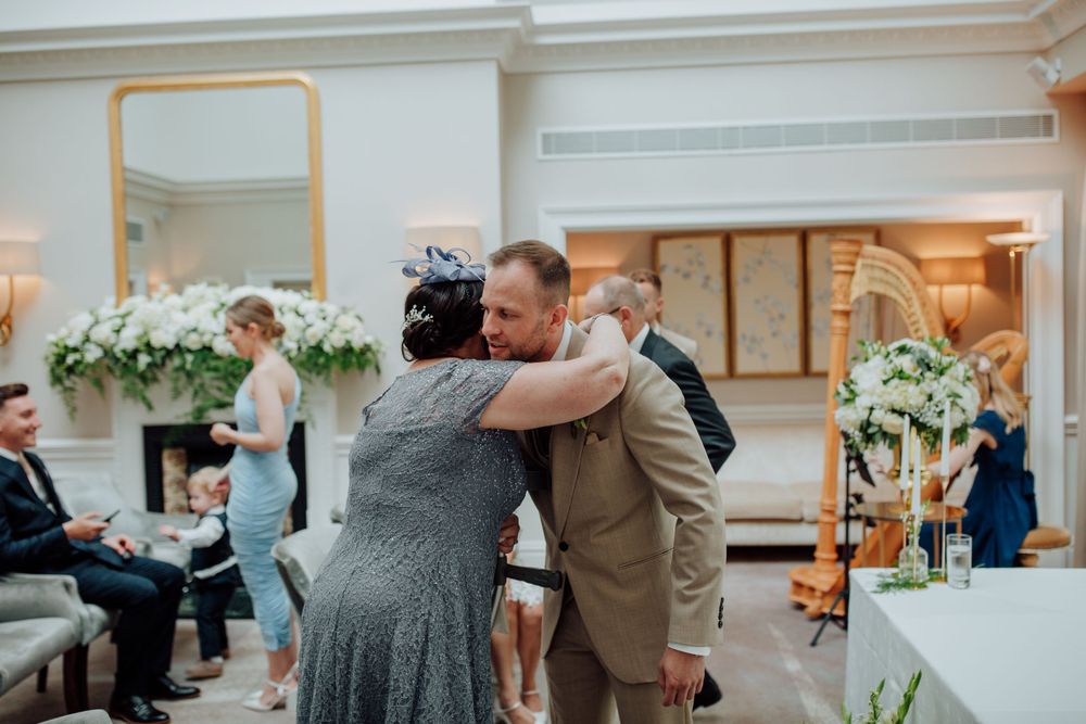 A couple shares an emotional embrace during a dance at an elegant indoor wedding reception decorated with white flowers.