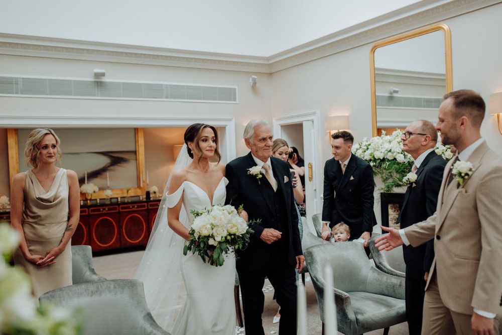 A joyous wedding celebration takes place in an elegant indoor venue with white floral decorations.