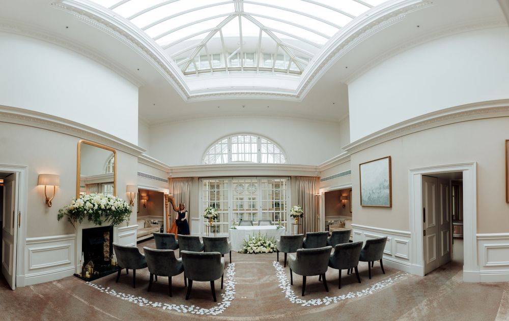 Elegant sitting room with glass ceiling skylight, black armchairs, and white floral arrangements in a luxurious interior space.