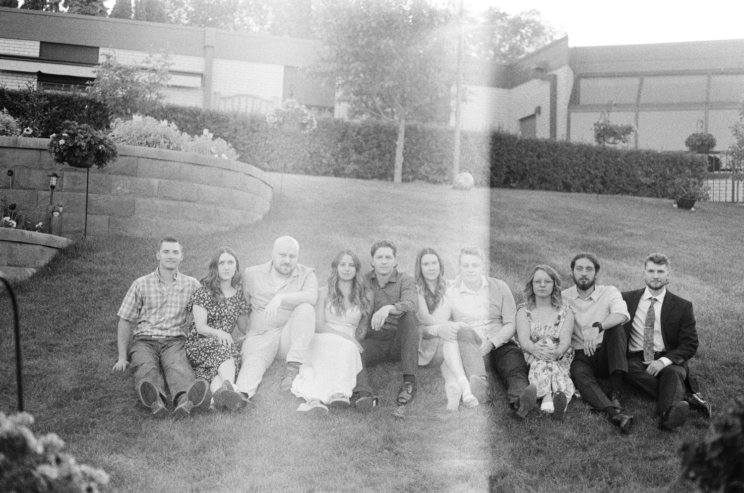 A vintage black and white photo of a group sitting together outdoors on grass.