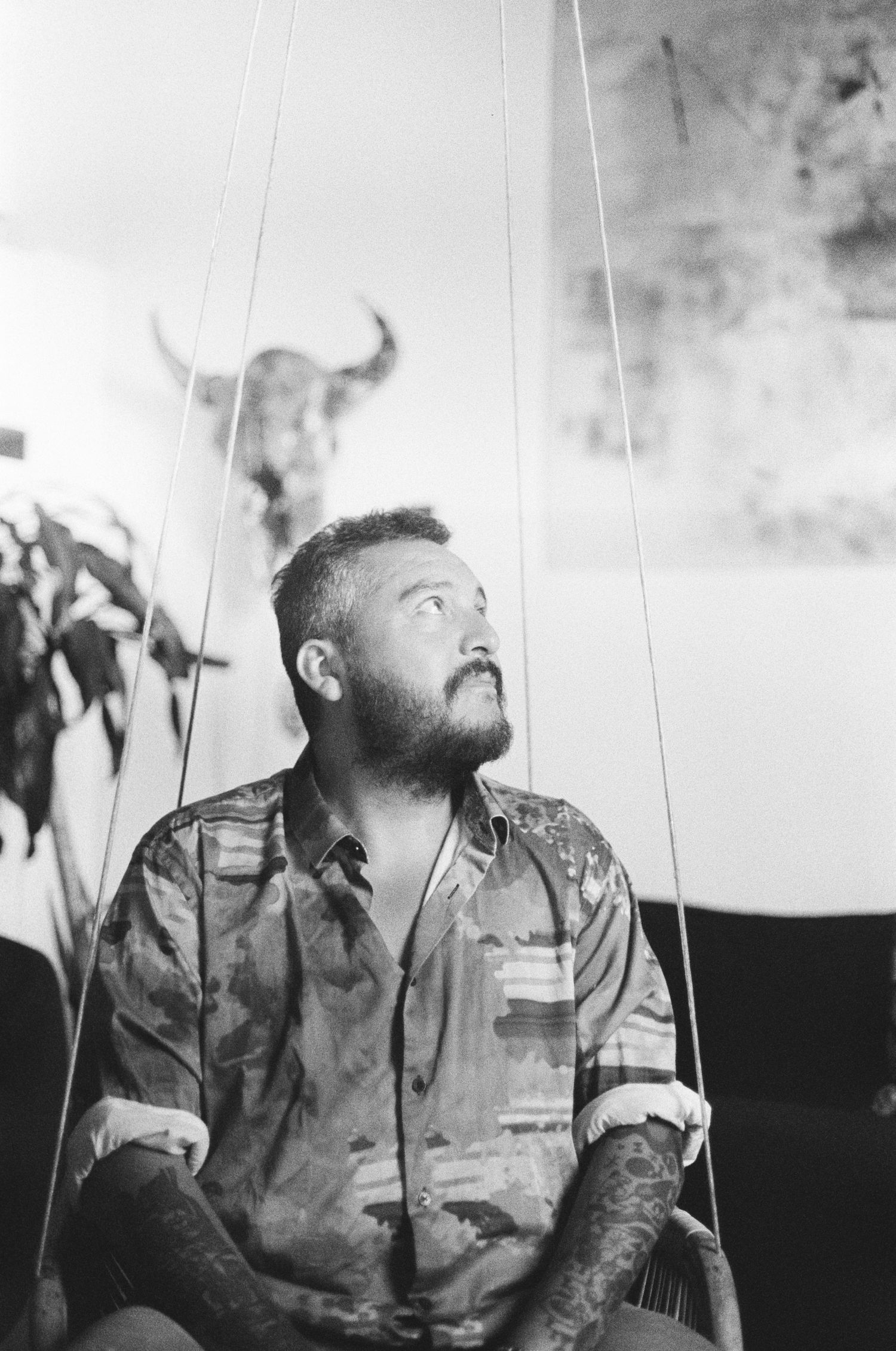 Artistic black and white portrait of someone with tattoos gazing upward.