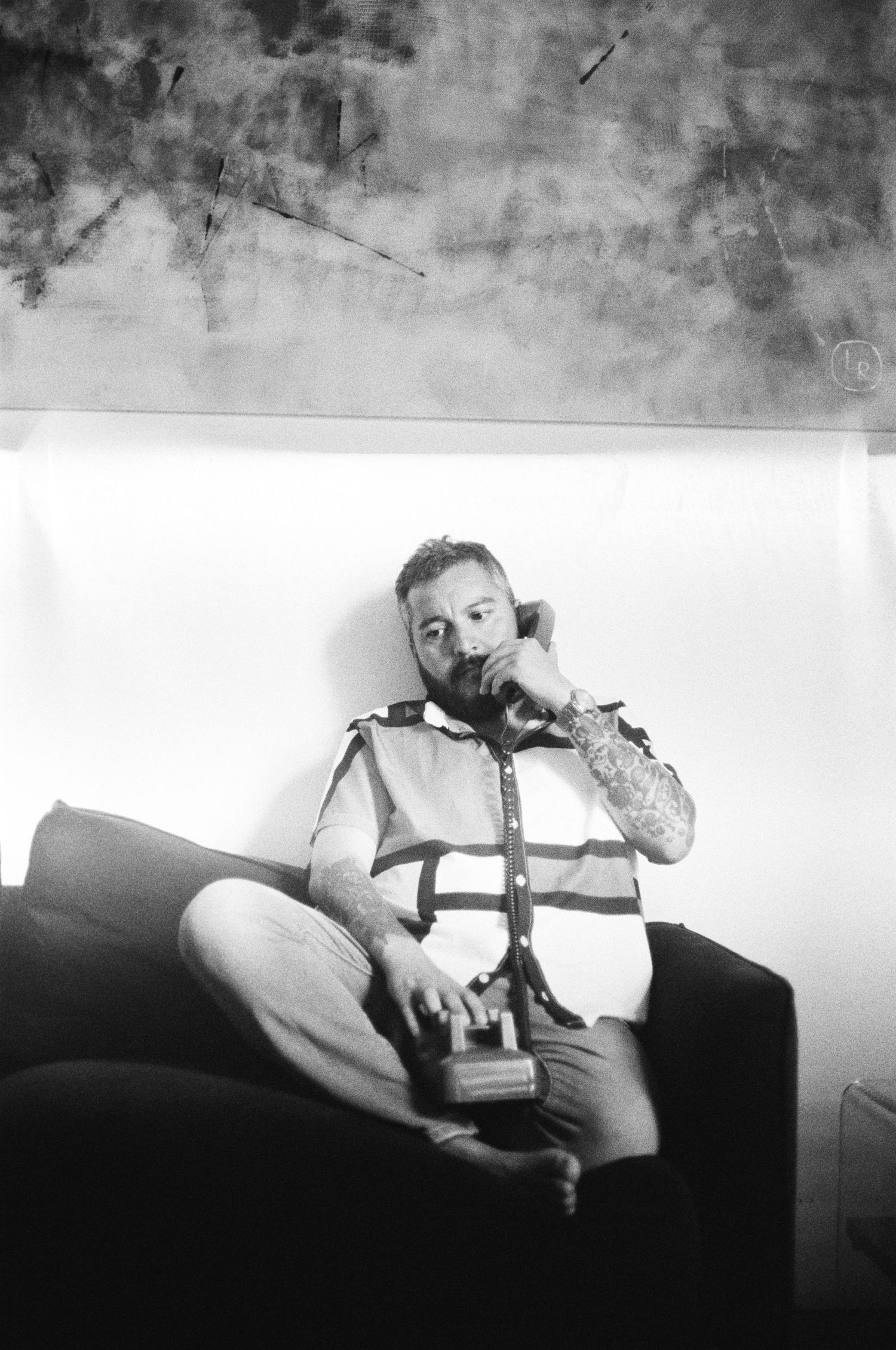 Black and white image of someone relaxing on a couch with tattoos.