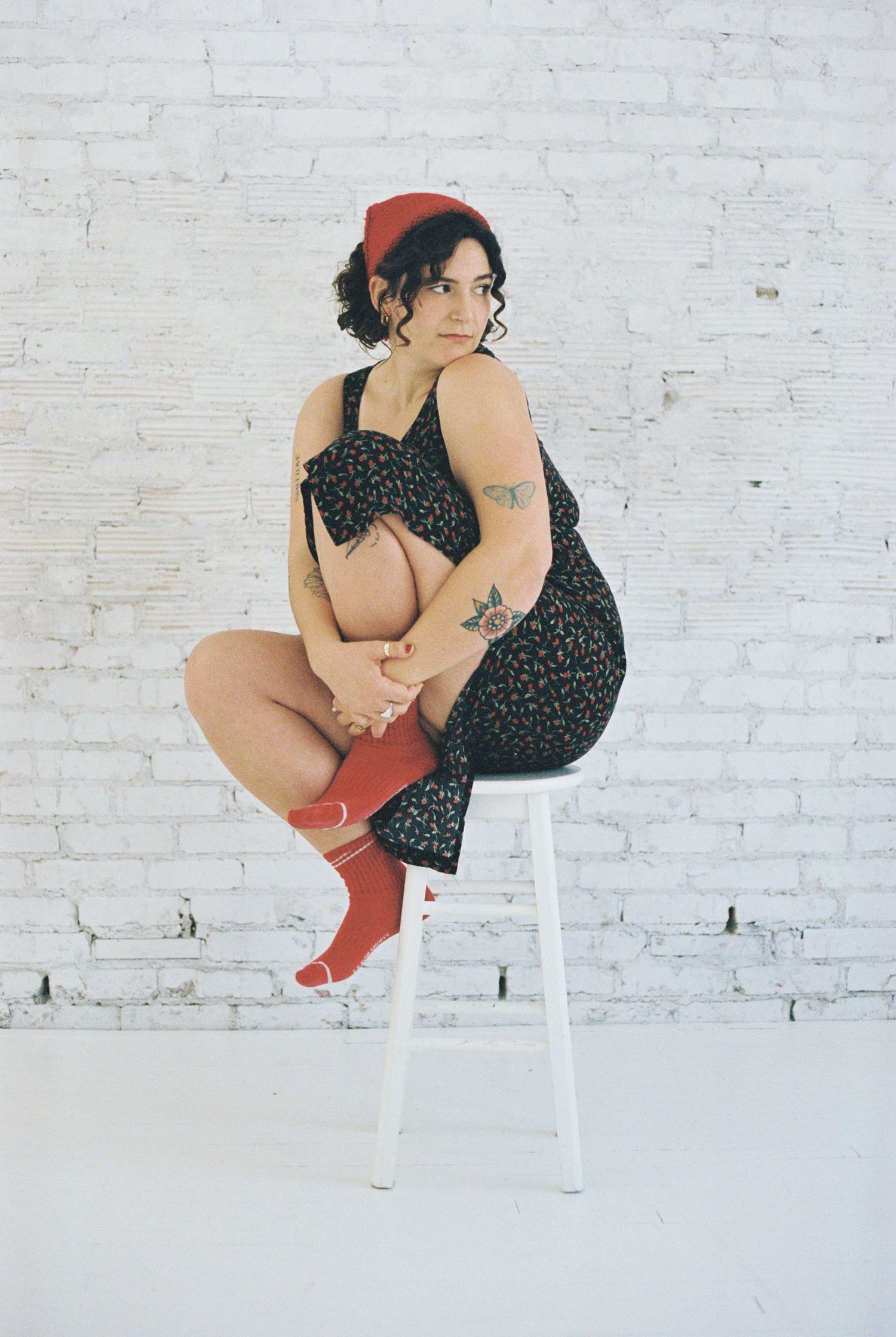 Stylish portrait on white stool wearing polka dot dress and red socks.