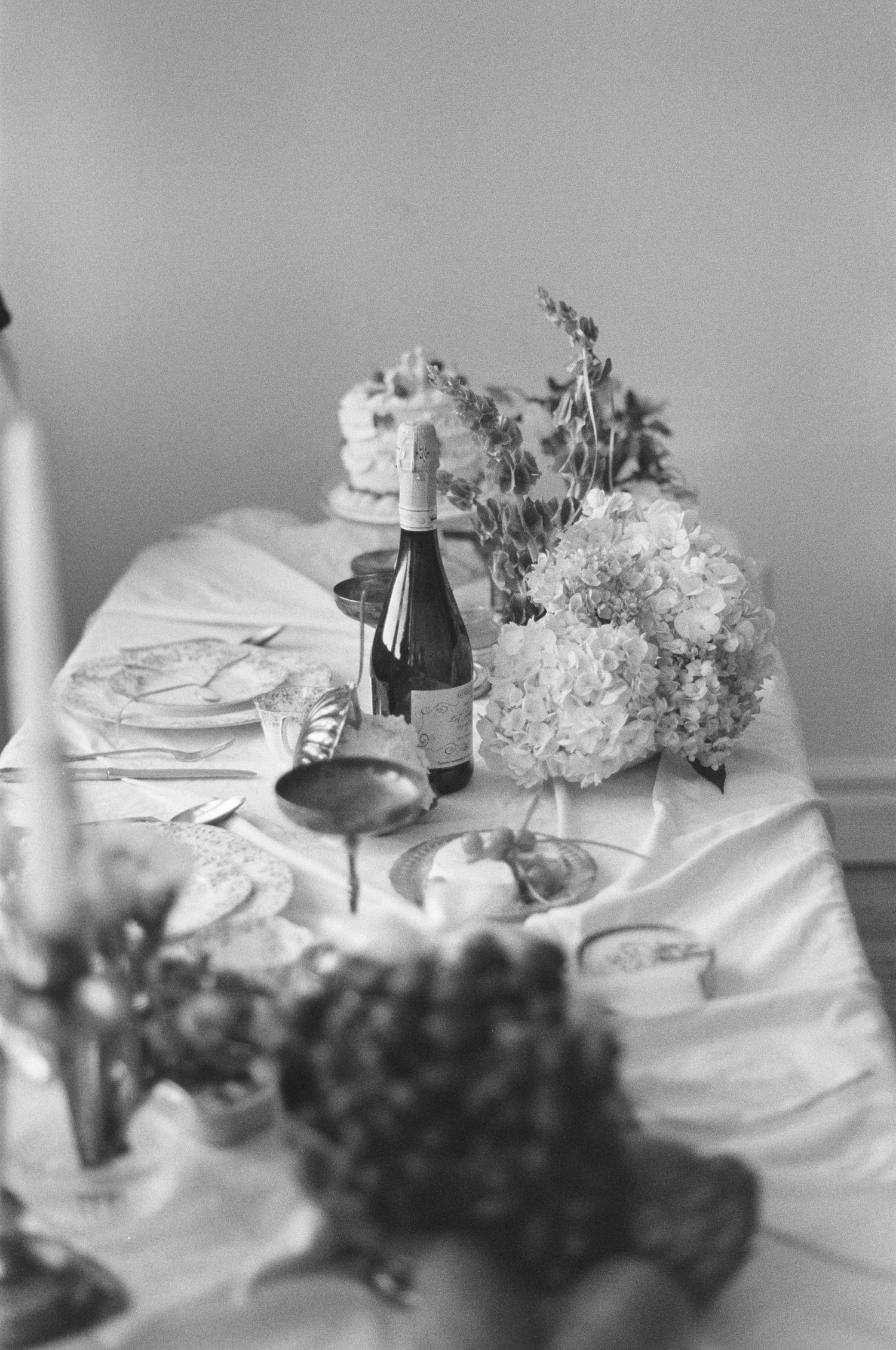 Black and white photo of wedding table with hydrangeas and wine bottles.