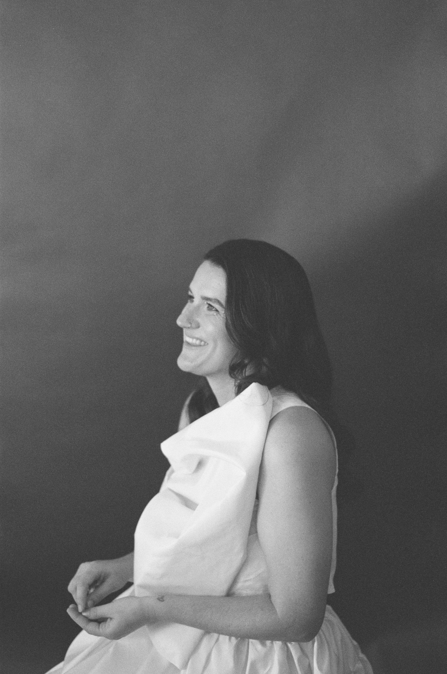 Black and white portrait showing joyful expression in white dress.