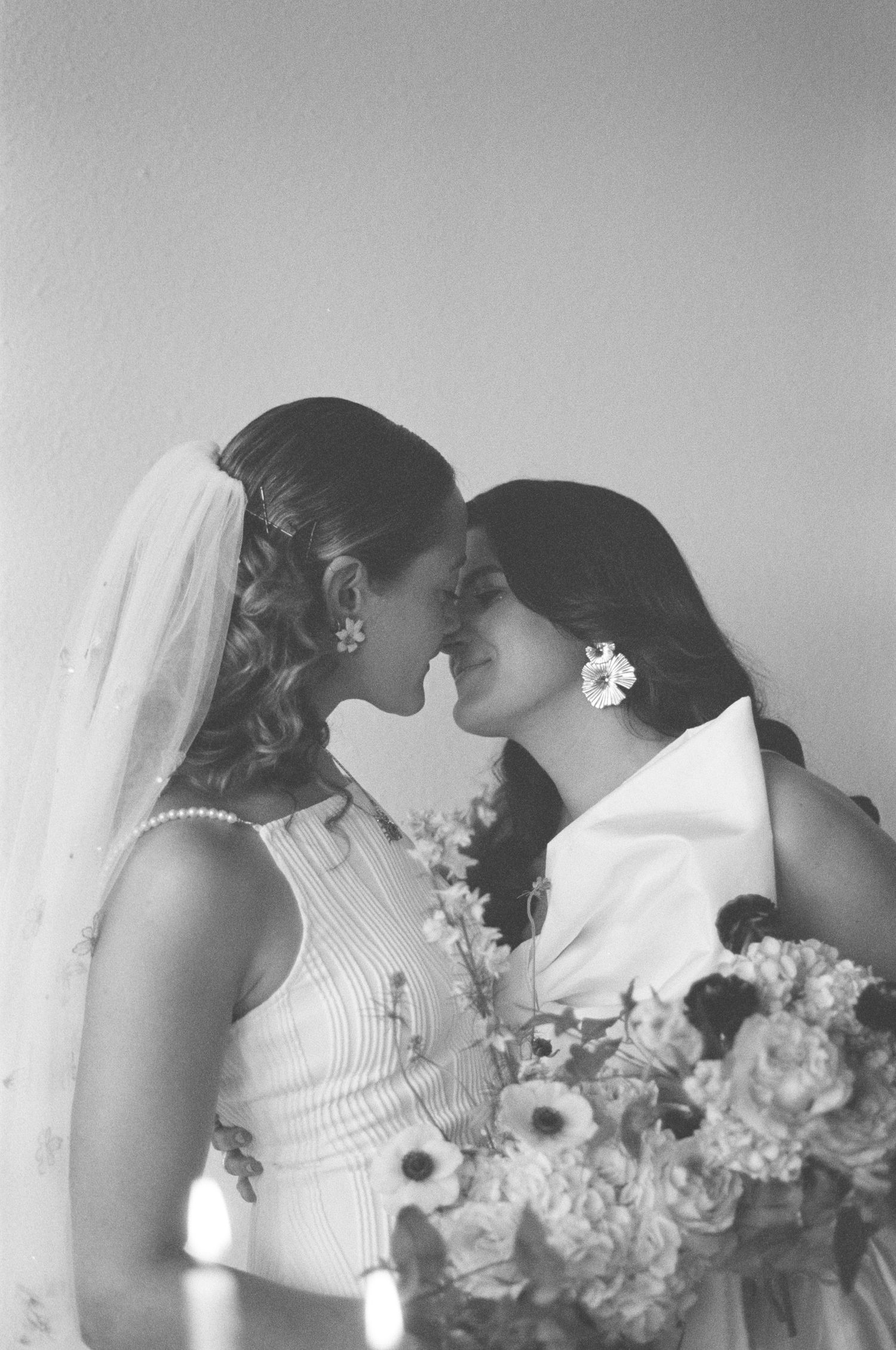Romantic black and white photo of two people sharing a tender moment with flowers.