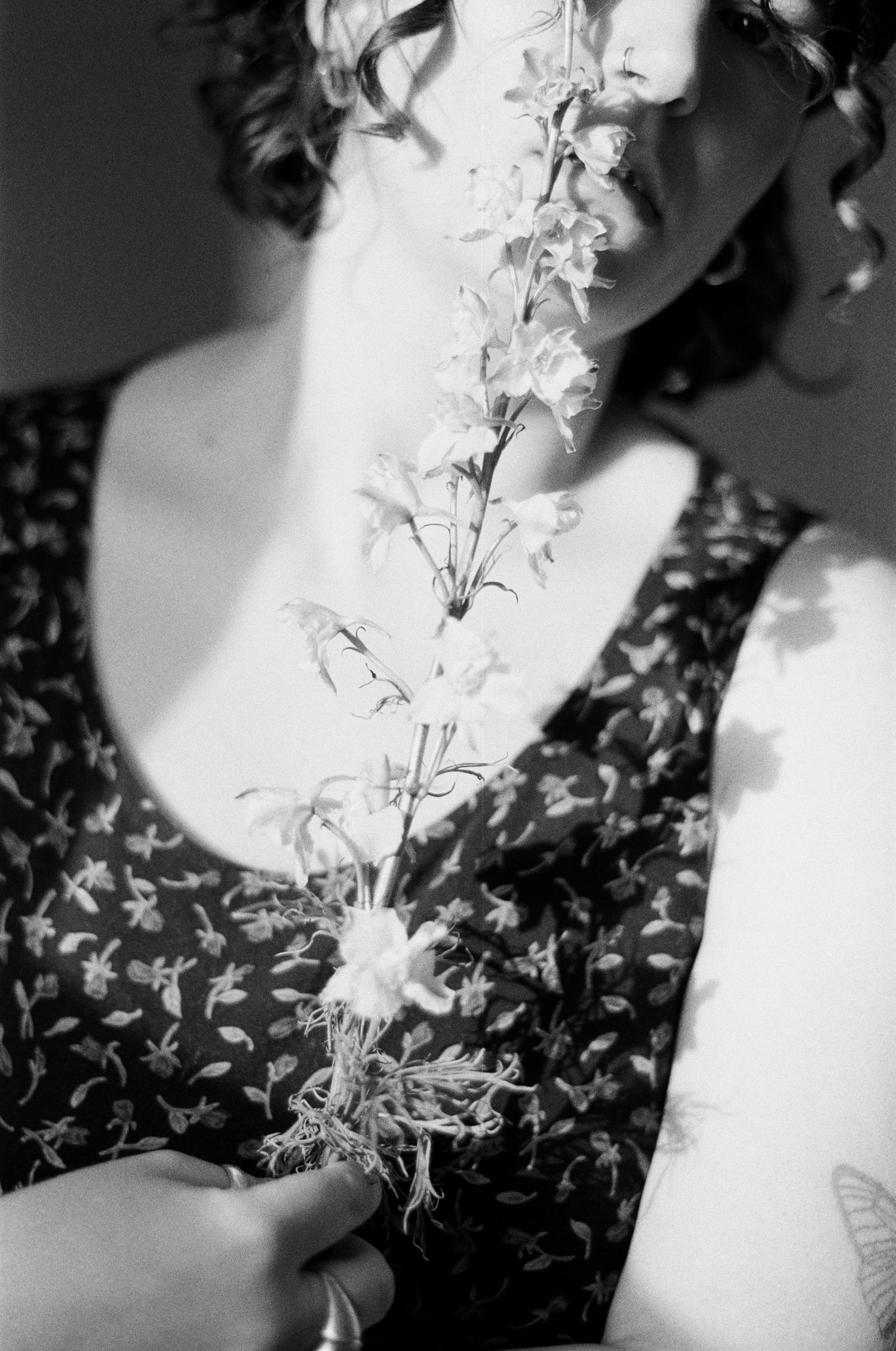 Artistic black and white photo of delicate white flowers against floral patterned dress.