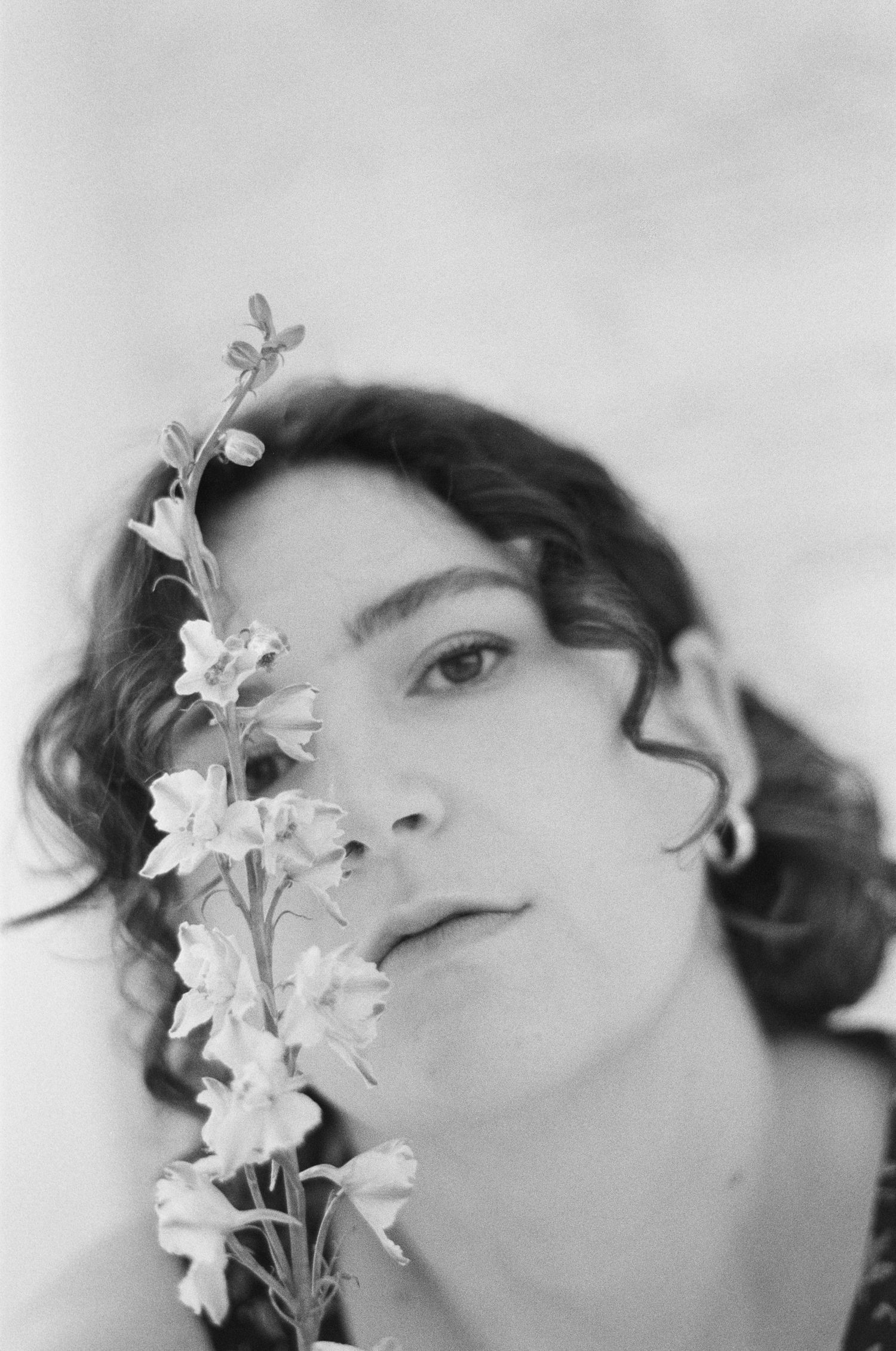 Ethereal black and white portrait featuring white flowers and natural curls.
