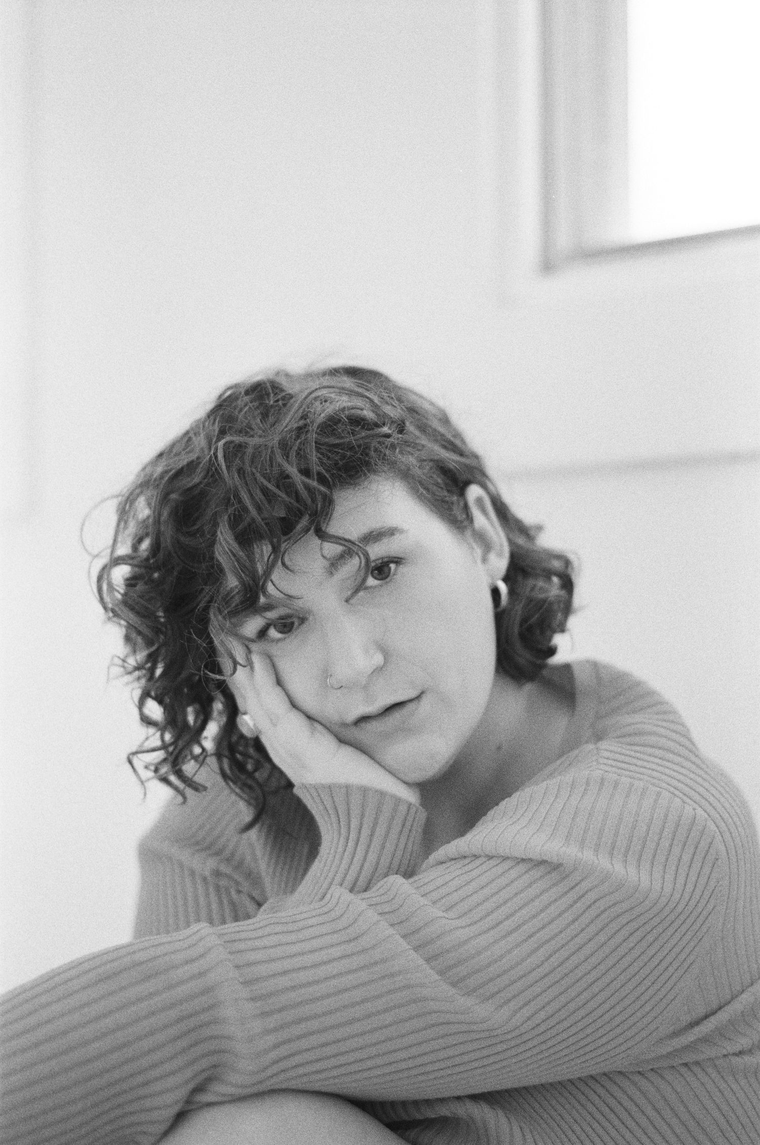 Moody black and white portrait showing contemplative pose in ribbed sweater.