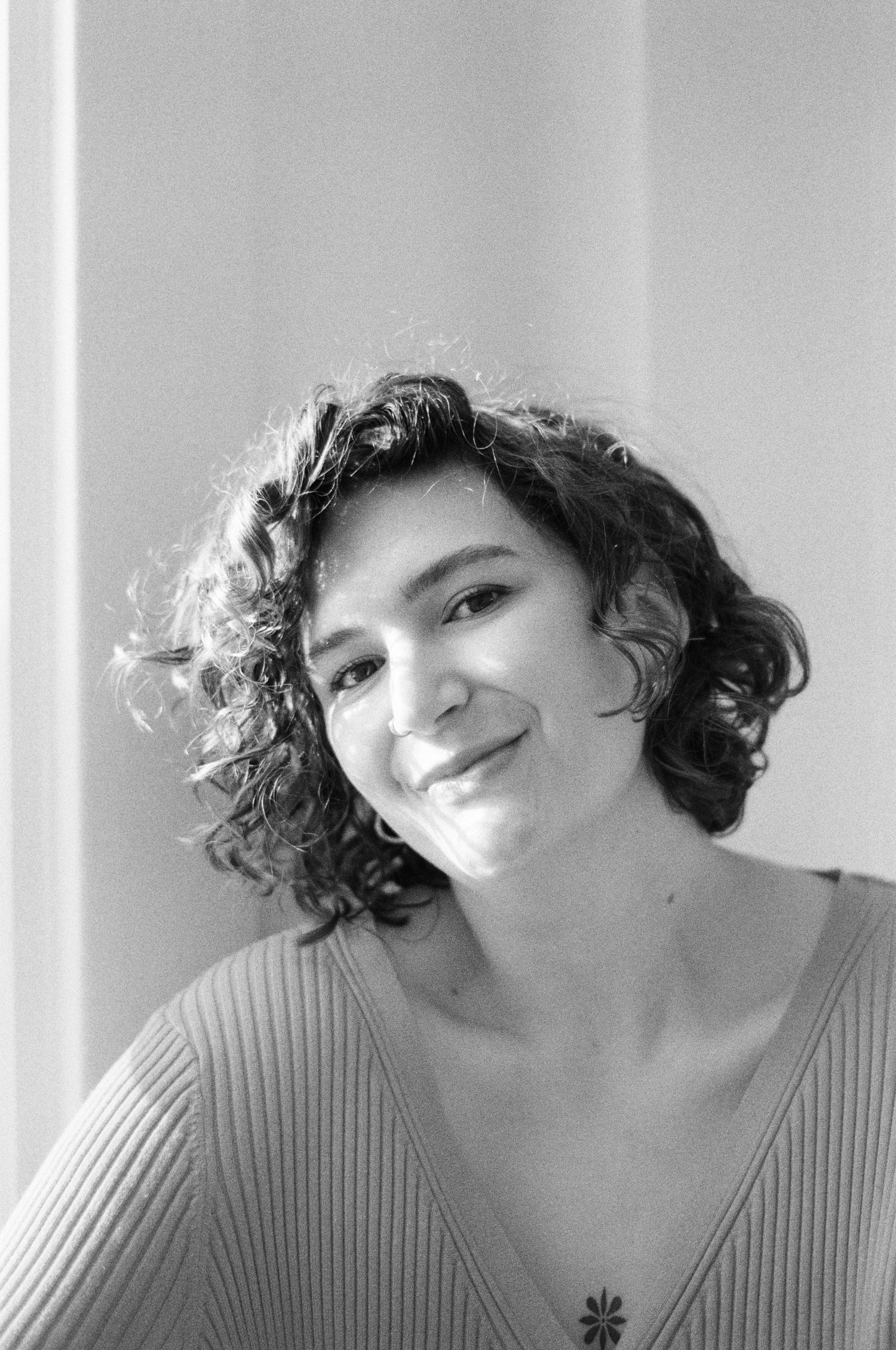 Intimate portrait in natural light showing soft smile and ribbed sweater.