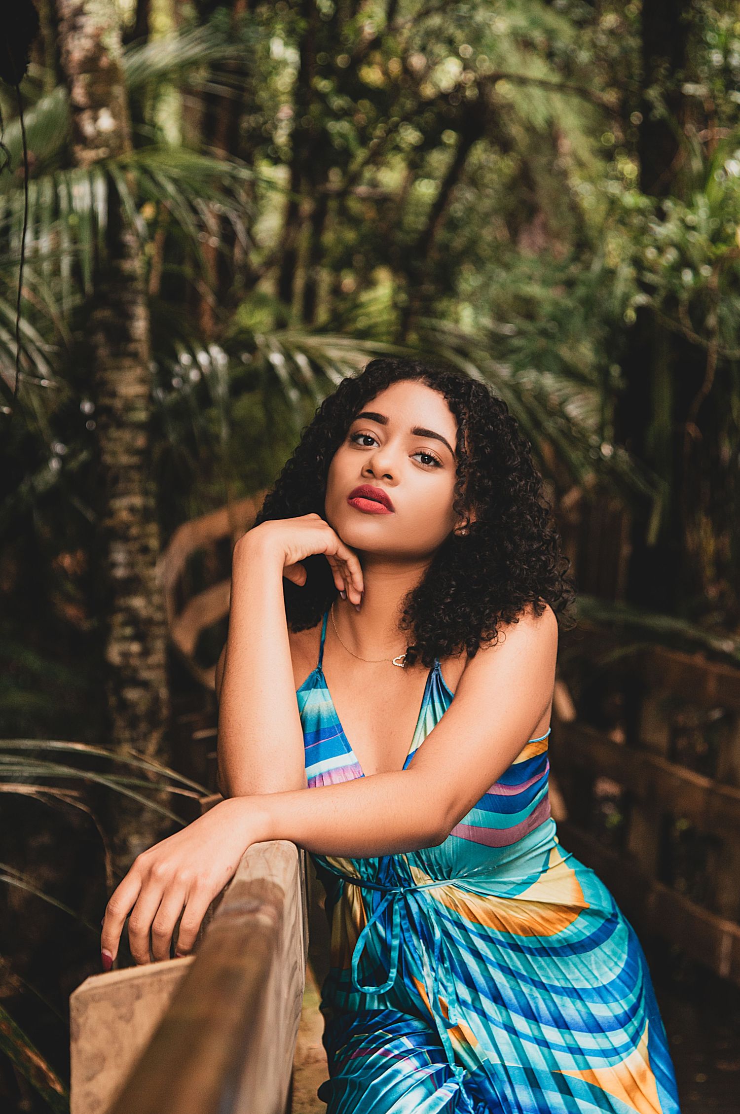 Teenage beauty and empowerment photography. Teenage girl in a blue and colour dress in the bush, leaning on a railing