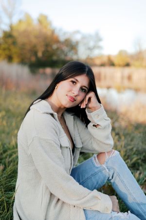Cozy autumn portrait in cream sweater and ripped jeans by a lakeside setting.