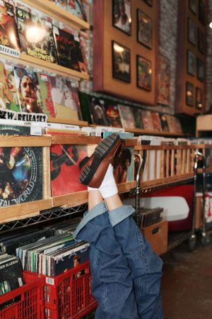 Person flipping through vinyl records in vintage music store.