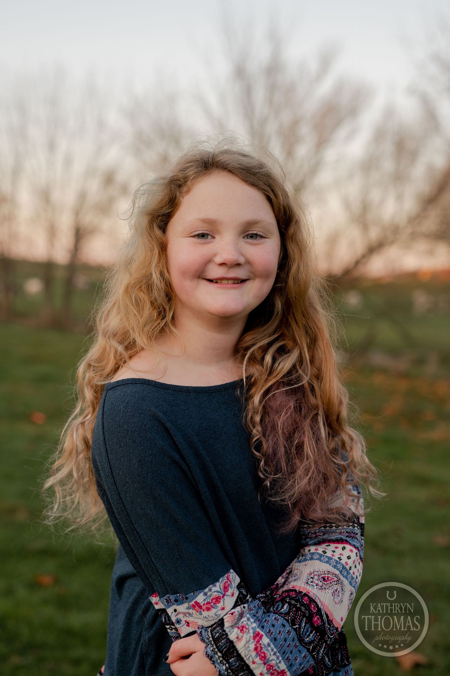 An outdoor portrait featuring a patterned sleeve sweater against a rural sunset backdrop.