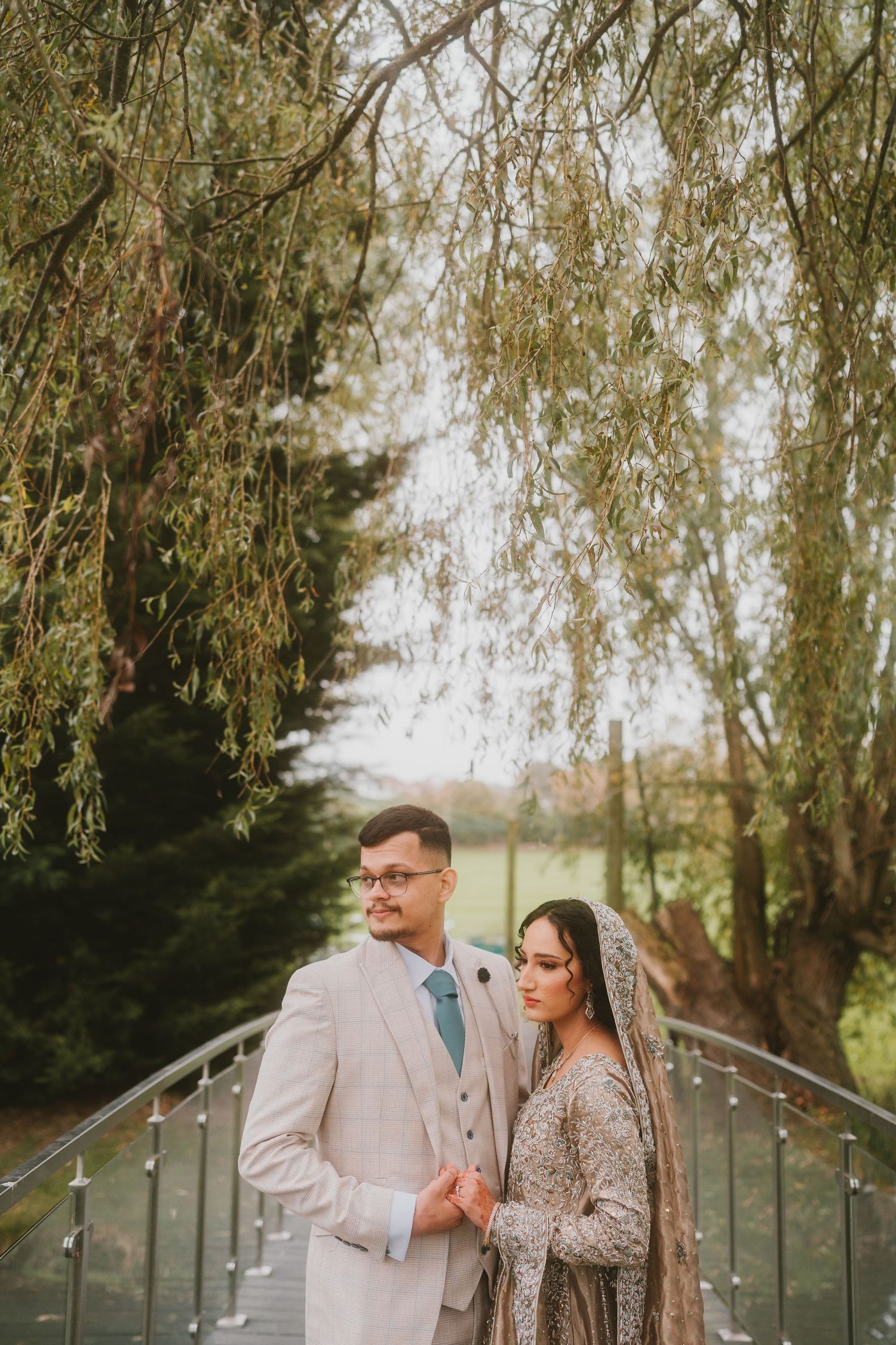Romantic wedding portrait under a weeping willow tree on a bridge.