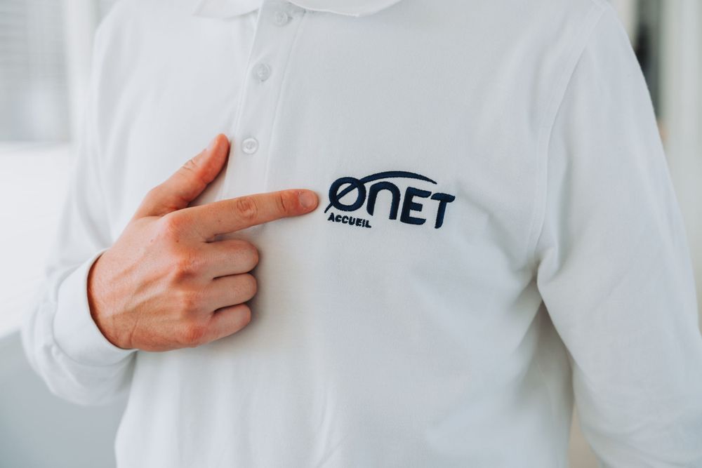 personne pointant le logo de la société sur la poche d'un tee shirt