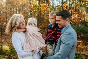 Family interacting with each other in front of fall trees for fall session captured by Maryland family photographer Mallory Bramlett