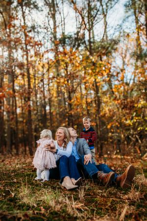 Family sitting in front of fall trees captured by Maryland family photographer Mallory Bramlett.