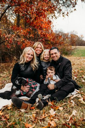 Family sitting in front of fall trees for family photoshoot captured by Maryland family photographer Mallory Bramlett.