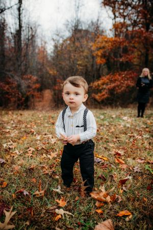 Toddler standing in front of fall trees for family portraits captured by Maryland family photographer Mallory Bramlett.