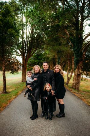 Family standing between trees on road captured by Maryland family photographer Mallory Bramlett.