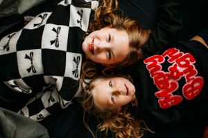 Sisters laying side by side for in home family photoshoot captured by Maryland family photographer Mallory Bramlett.