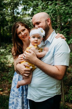 Mother and father with infant in backyard for in home family photoshoot captured by Maryland family photographer Mallory Bramlett.