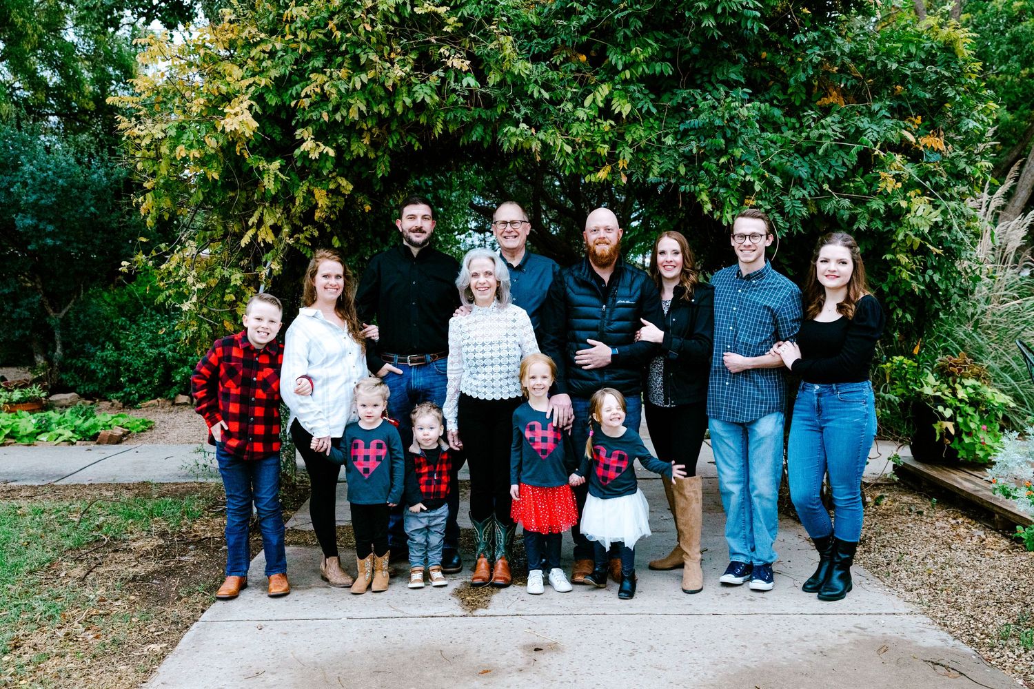 Large family group portrait with adults and children standing together on a garden path.