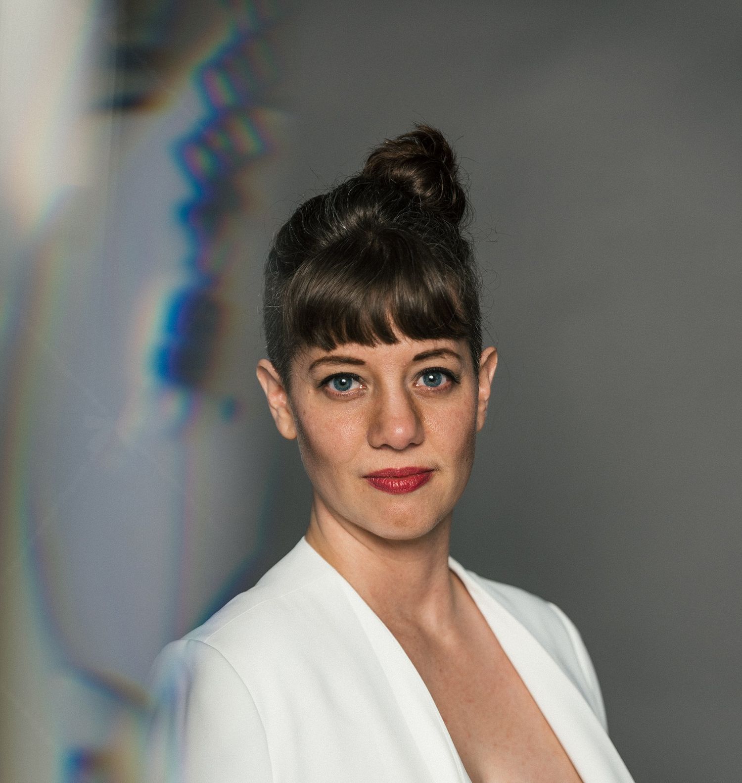 A chic portrait featuring a white blazer and classic updo against a dramatic background.