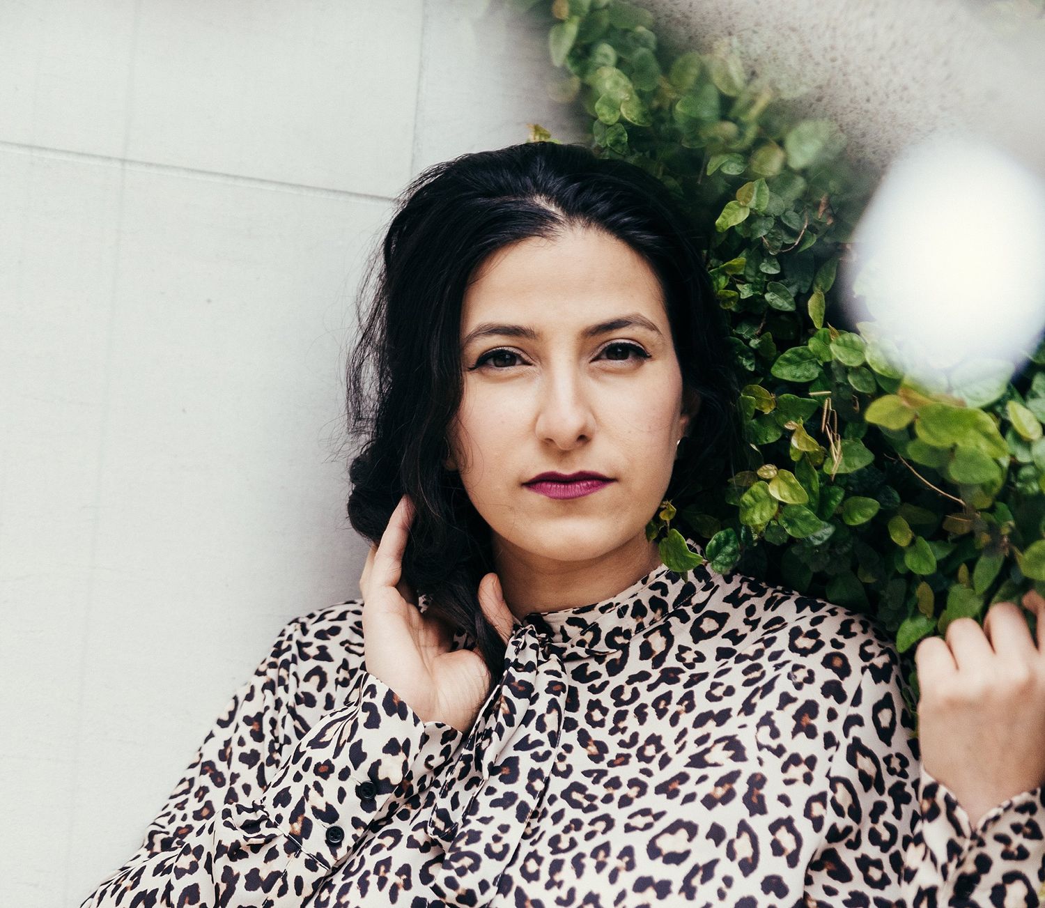 A fashionable leopard print top styled against a white wall with greenery.