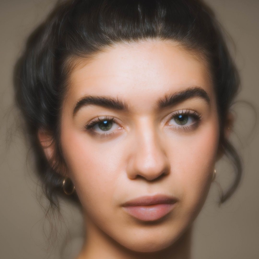 Portrait of a person with dark hair against neutral background showing striking facial features.