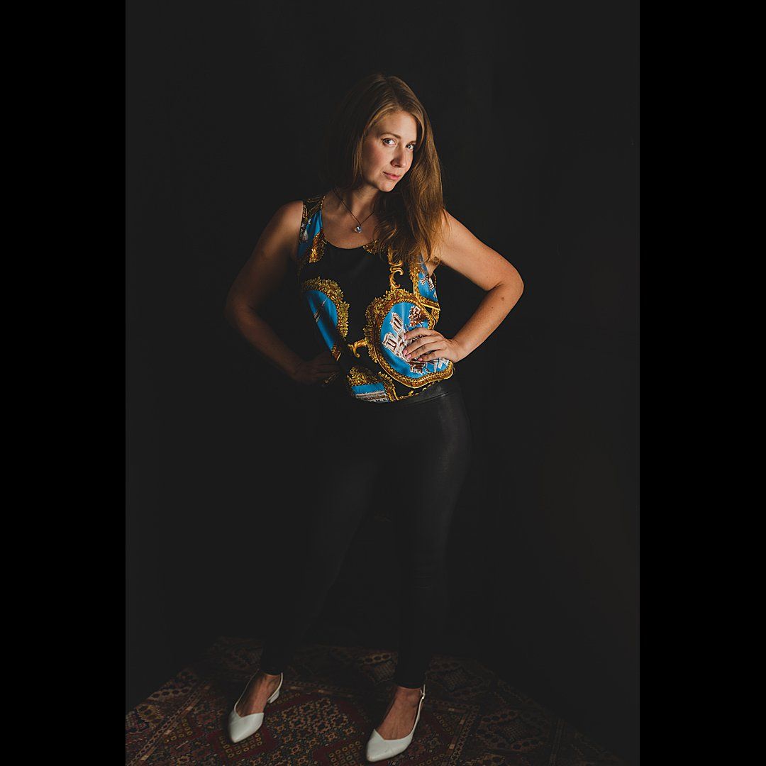 Fashion portrait of person in patterned top against dark background.