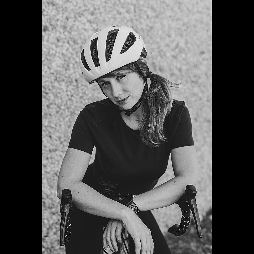 Black and white portrait of a cyclist wearing a white helmet and black shirt.