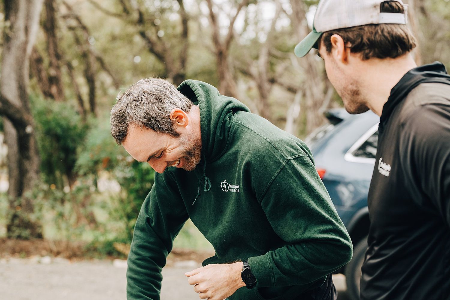 Two people in hooded sweatshirts working together outdoors.