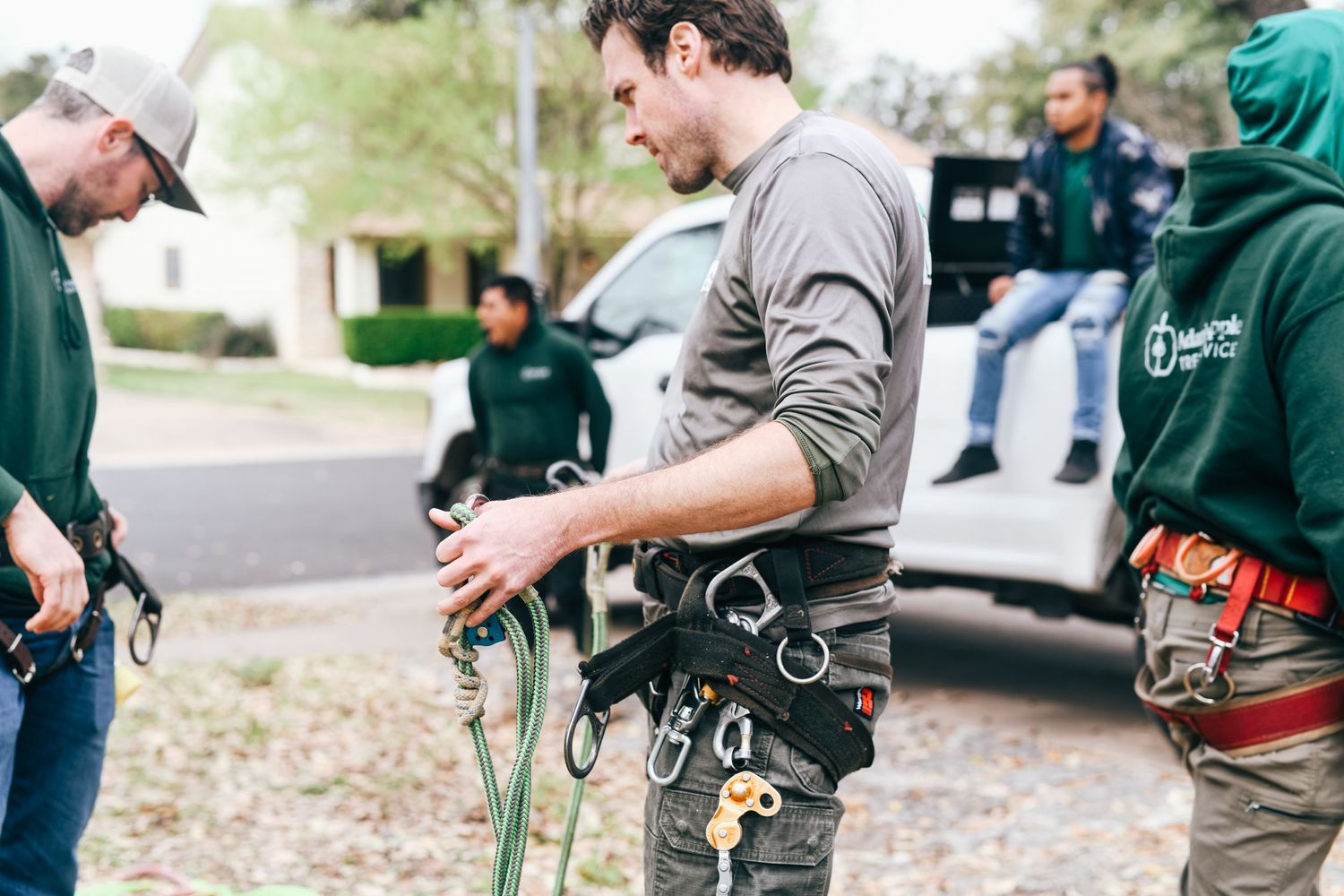 Tree service workers preparing equipment and safety gear for climbing job.