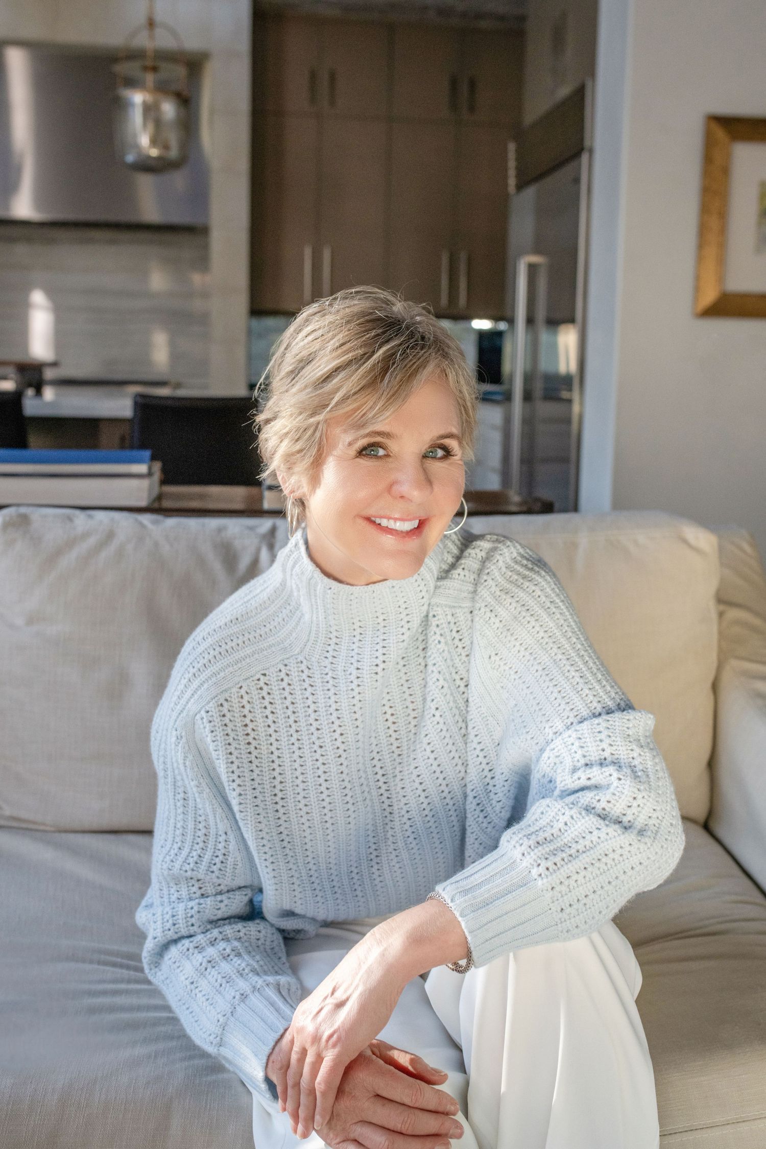 A cozy winter look with a chunky knit sweater while relaxing on a neutral colored sofa.