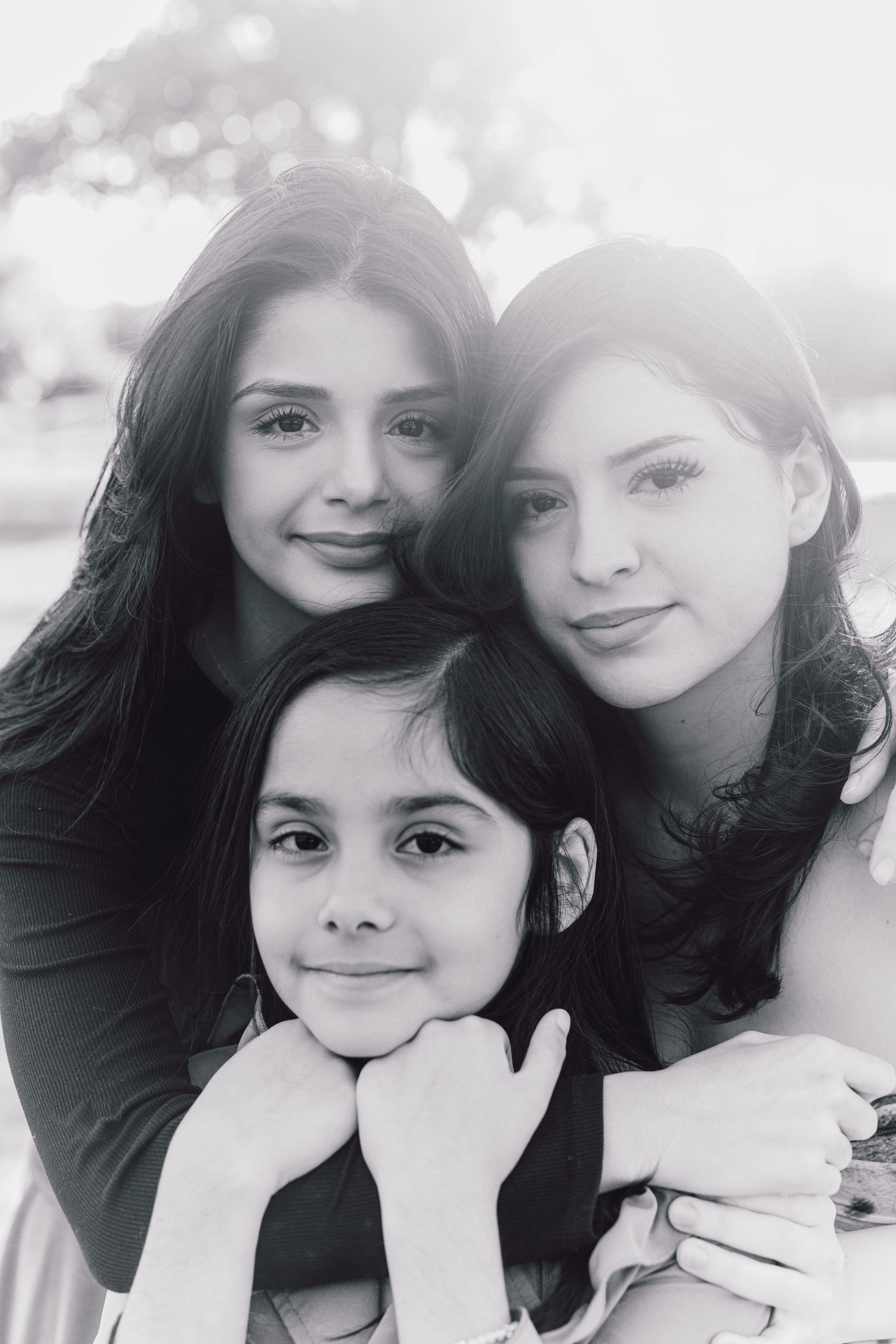 Black and white portrait of three people posing together with matching smiles.