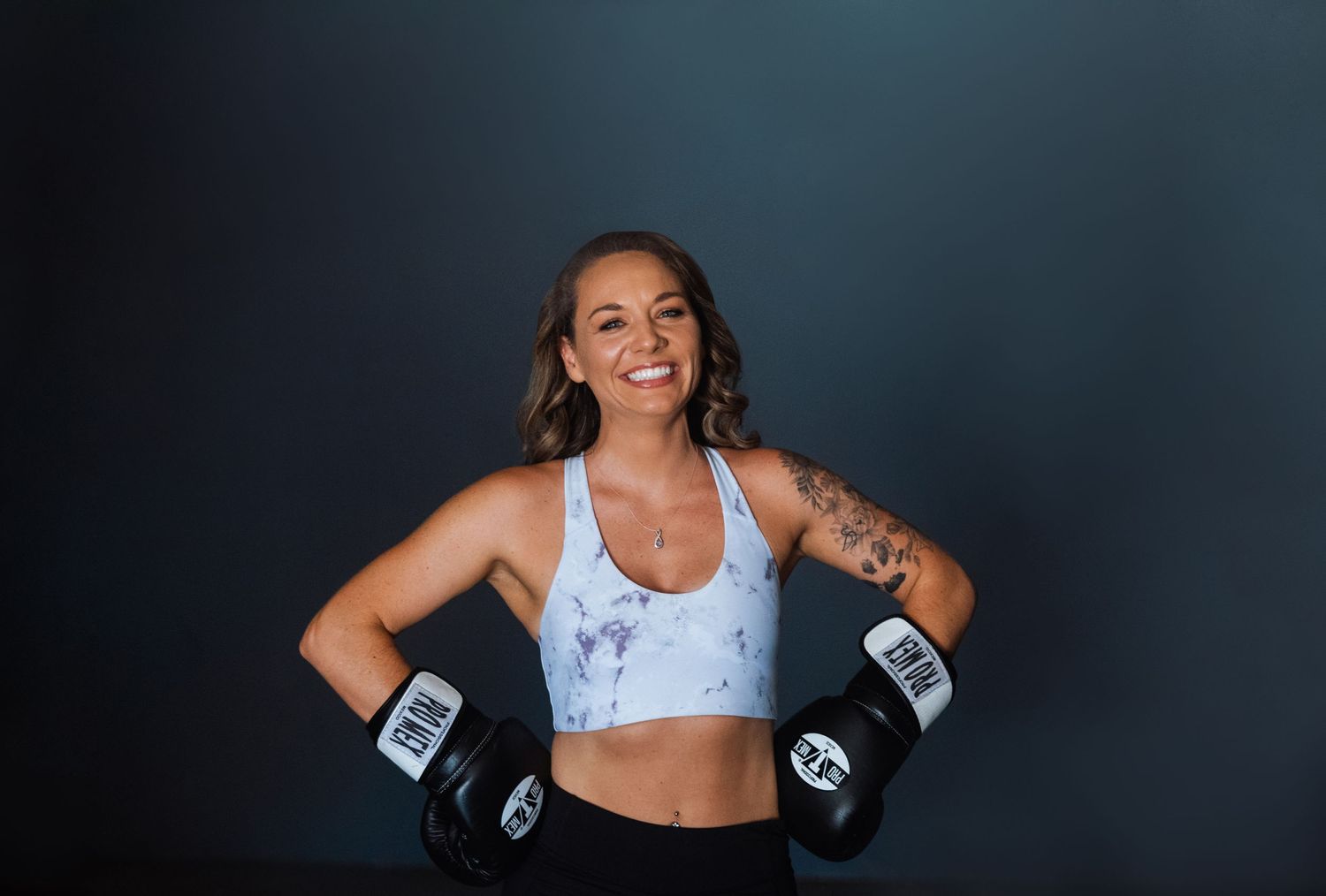 Fitness portrait with boxing gloves and athletic wear against dark background.