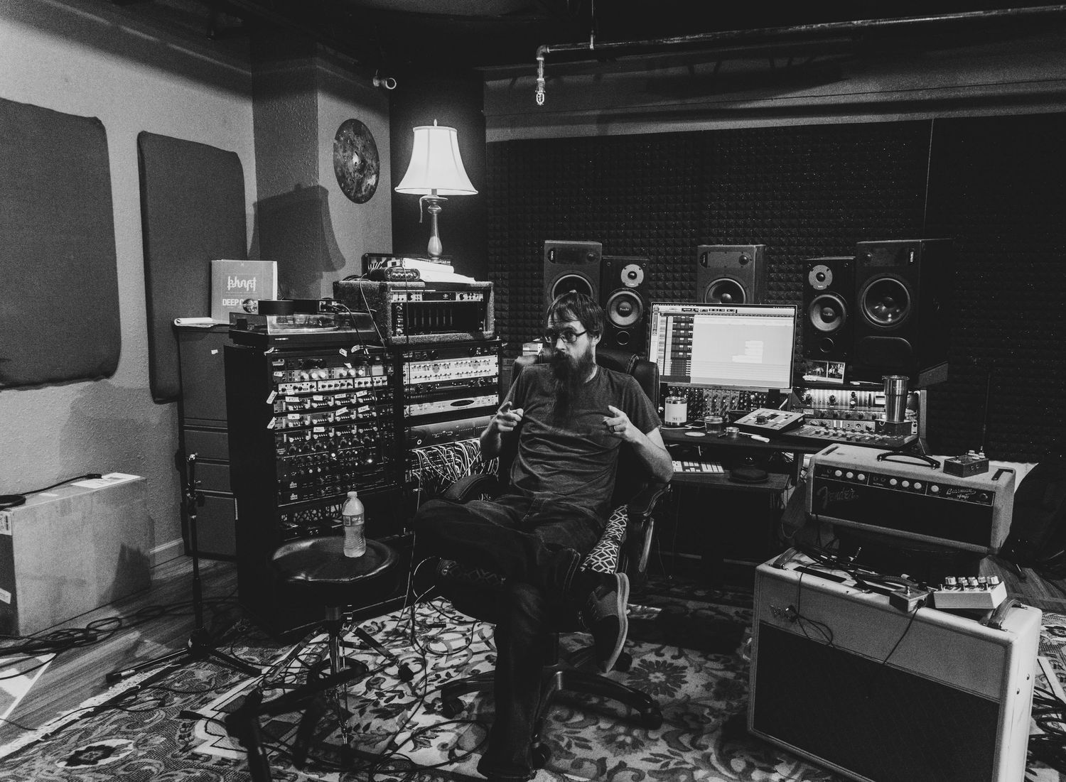 Music producer working in dark recording studio with vintage equipment and ambient lighting.