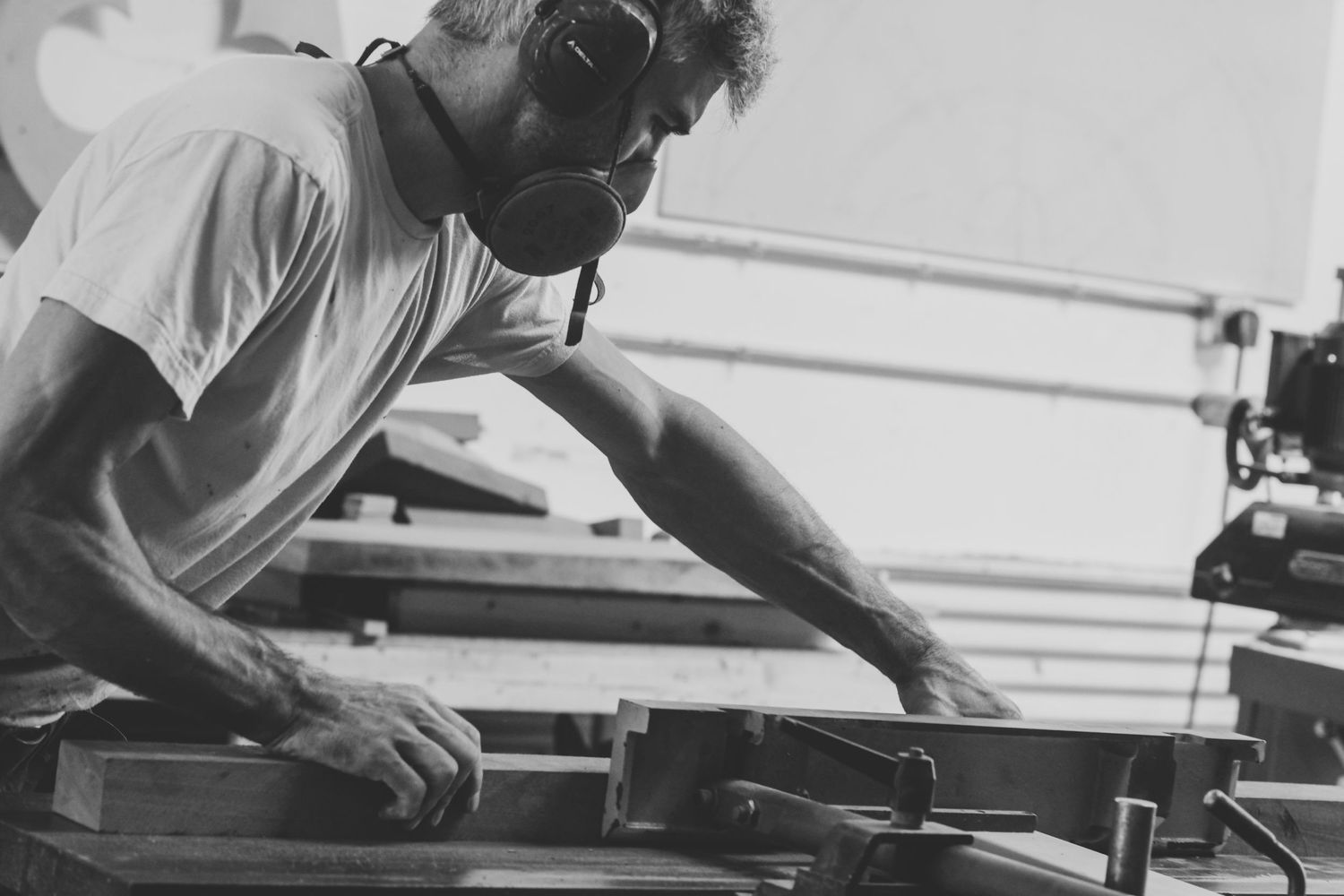 Craftsman working intently at workshop bench in vintage black and white photograph.