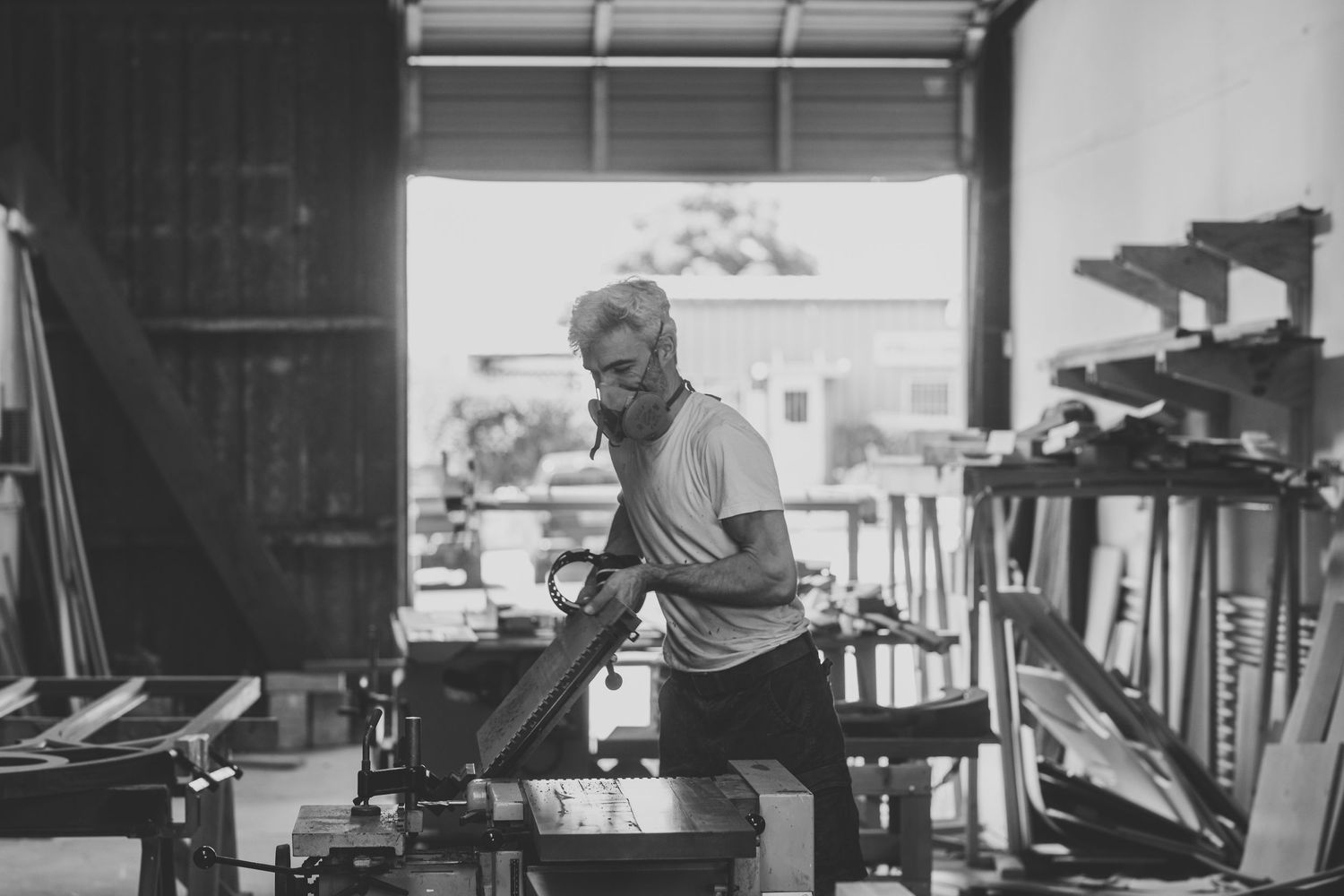 Artisan focused on detailed work at industrial workspace in monochrome setting.