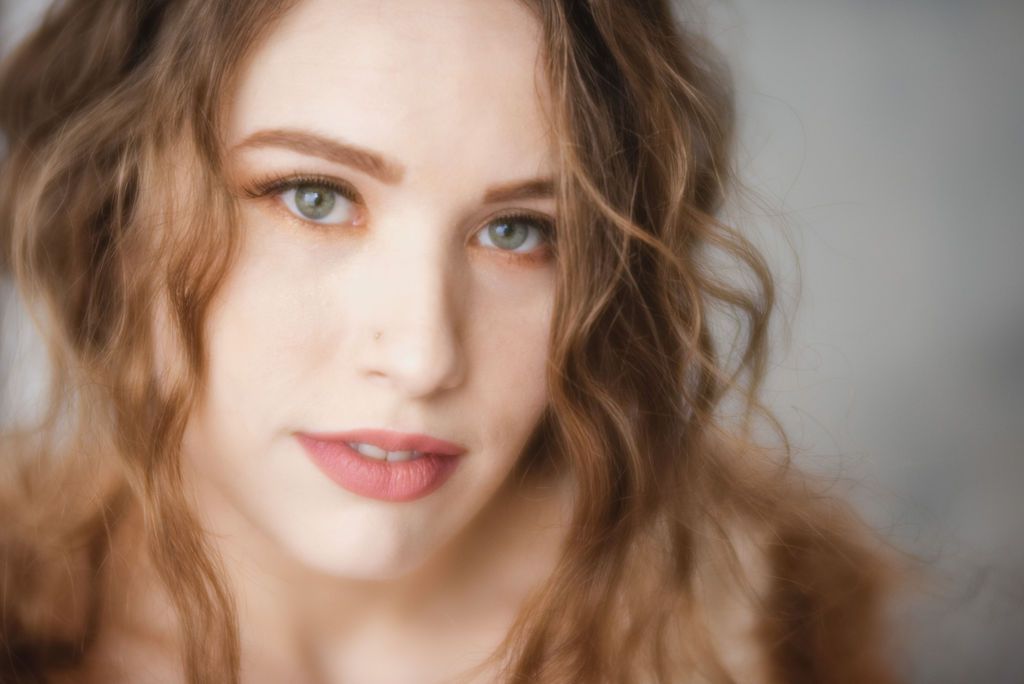 Soft beauty portrait showing natural makeup and wavy brown hair.