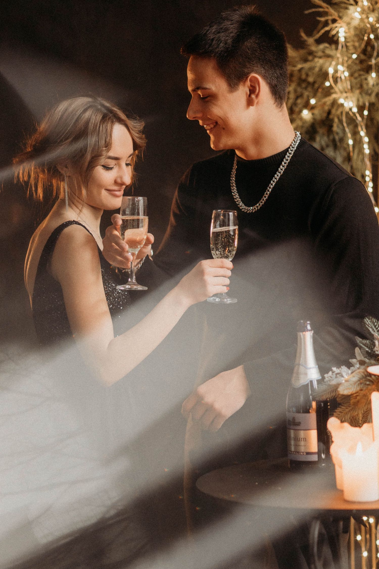 Romantic candlelit scene with champagne glasses and holiday decorations.