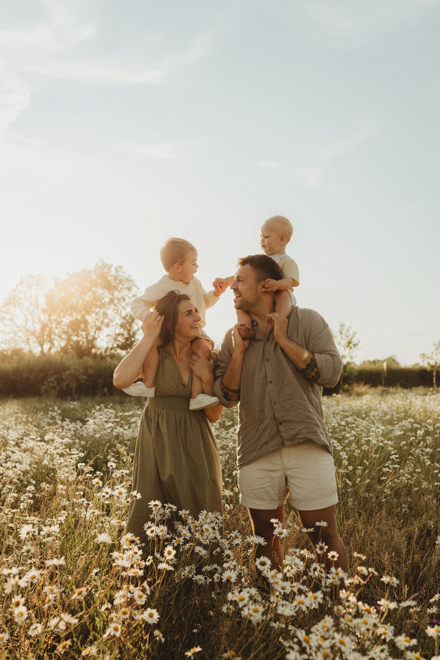 Dynamic family photo capturing playful interaction against cloudy sky.