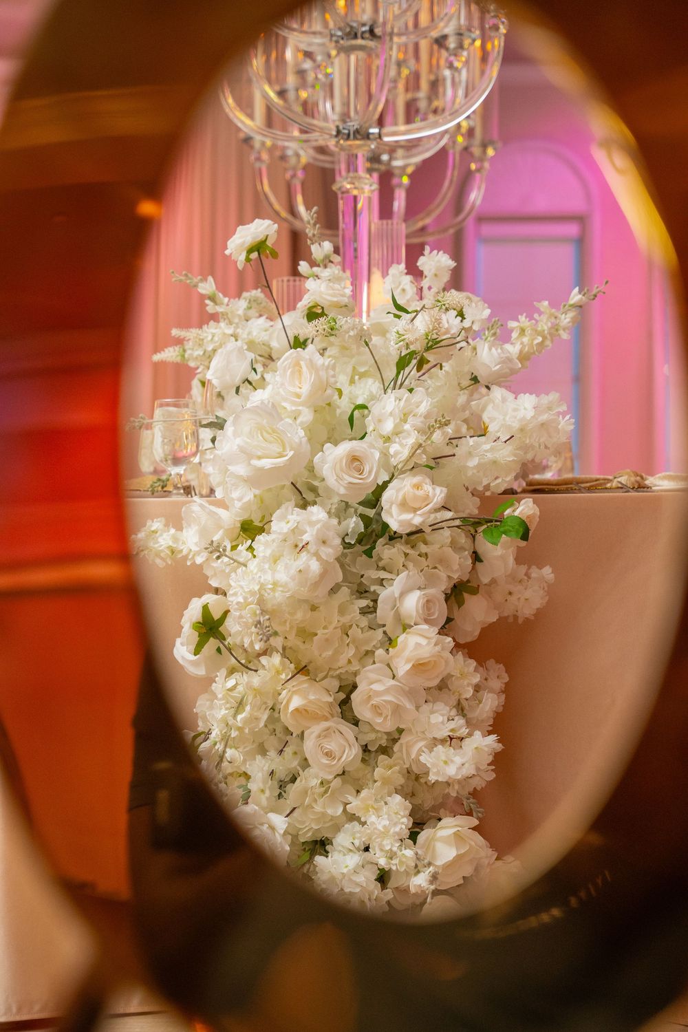 Elegant white rose floral arrangement cascading down a table centerpiece at a wedding reception.