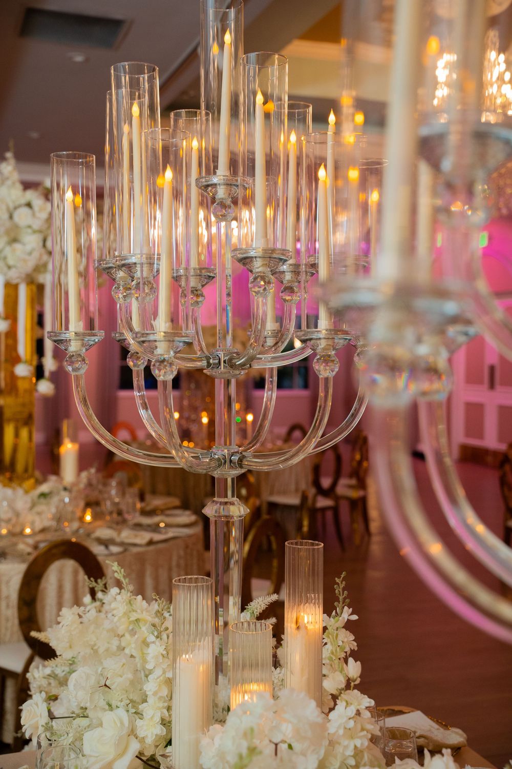 Elegant crystal candelabra with lit candles and white floral arrangements at a romantic wedding reception.