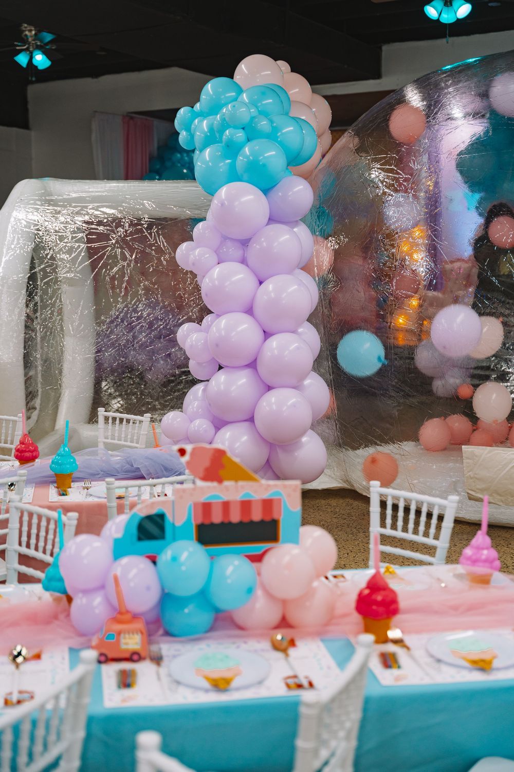 Colorful balloon column in pink and blue at a festive children's party with decorated tables and chairs.