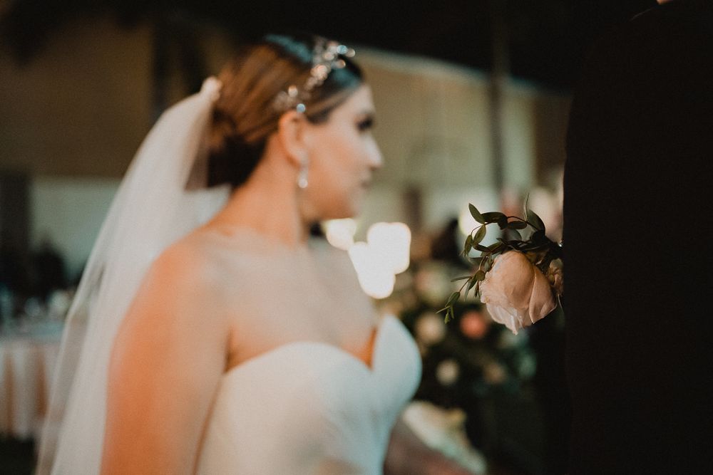 Close-up of groom’s flower detail, with the bride beautifully blurred in the background